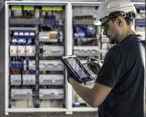 Man, an electrical technician working in a switchboard with fuses. Installation and connection of electrical equipment. Professional uses a tablet. SSUCv3H4sIAAAAAAAACpySz27DIAzG75P2DhHnRkoDSZO+SrWDA7SxSqEC0mmq+u7jT1Kx627xz/ZnfzjPz4+qIhM45ORYPWMUYlRqcd6CR6MDbnYrt1ILaUvysLRvSgBYRlKgNxZBlXACz2cNNxmgXpSK+JWSxHnwi5Mu7rIiDl5egkaGb4m88CnH1ZZIydARUoTsCuaWKbENZfF/deaPr7fhi9T8Jy1cGLFSSchGTrmUXL+9tLfSGiwCTeHqYTioWEALJcA7WPjTd7fIUV8KYvyc7rIpcbNob+NWbzNEGXOHScVXP4cxcuMzOBfKxcaL2Tz8BeZWzNHGJ0+rKhHhODHcU9qxoWUto2zo+7Fr14J80BmDTlpnEwoxv6IoXWHcgLCmo6zlh3oQdKzZfuzroWf7mk+s6xt+YOfzEG7x+gUAAP//AwAqfENsuQIAAA==